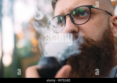Portrait of man sitting and smoking pipe. Stock Photo
