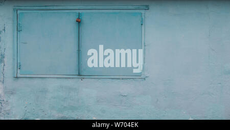 Wall with closed metal window. Light-blue color Stock Photo