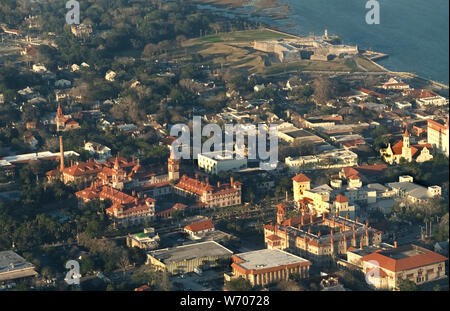 The sun was setting when this aerial view was taken of historic St. Augustine on the east coast of Florida, USA. The sprawling red-roofed building with twin towers (left center) is home to Flagler College, a four-year liberal arts college that originally was the Ponce de Leon Hotel, a luxury resort built by American industrialist Henry Flagler in 1888. The coquina-stone fortress (rear right) is the Castillo de San Marcos that overlooks Mantanzas Bay and dates to 1672. St. Augustine claims to be America's oldest continuously inhabited city since its founding as a Spanish territory in 1565. Stock Photo