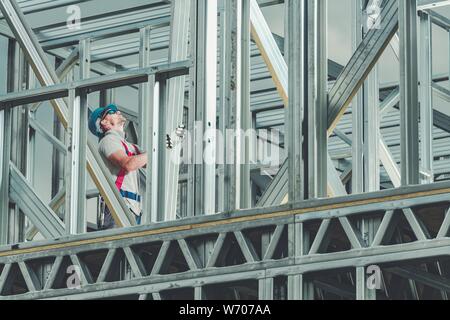 Construction Worker on Duty. Caucasian Men Building Steel Frame Building Structure. Industrial Theme. Stock Photo