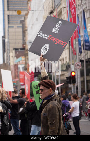 Middle aged protester wearing beret with grey goatee holding a black Climate Emergency sign at Climate Emergency demonstration in downtown Melbourne Stock Photo