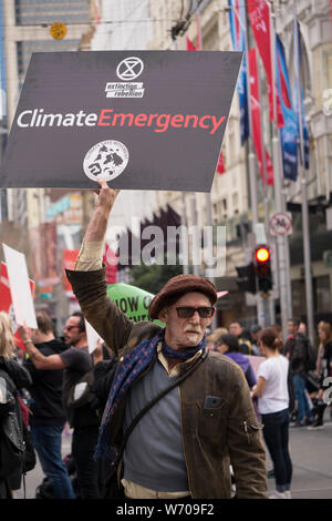 Middle aged protester wearing beret with grey goatee holding a black Climate Emergency sign at Climate Emergency demonstration in downtown Melbourne Stock Photo