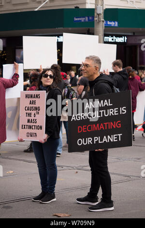 Middle aged protesters holding black 'animal agriculture is decimating our planet' sign in Melbourne, Australia climate protest march. Stock Photo