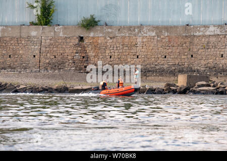People in an inflatable boat floating on the Amur river along the shore. Stock Photo