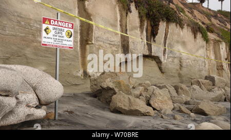 Warning sign and caution tape at Grandview Beach in Encinitas, CA - site of a deadly bluff collapse that killed three people on August 2, 2019 Stock Photo