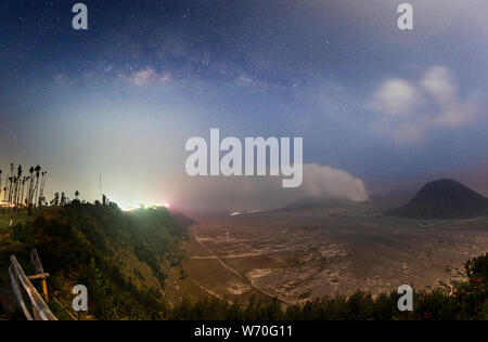 Mount Bromo covered with mist and milky way galaxy stars shining in the sky at night, Java Indonesia Stock Photo
