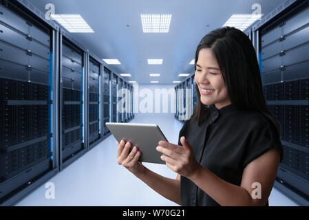 Asian woman smiling with digital tablet in server room Stock Photo