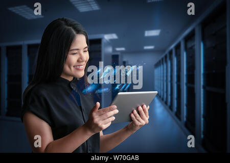 Asian woman smiling with digital tablet in server room Stock Photo