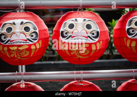 Daruma dolls. The Japanese lucky symbolic dolls hanging in the row with text translation “fortune”. Stock Photo