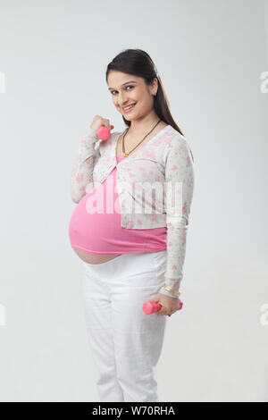 Pregnant woman exercising with dumbbell Stock Photo