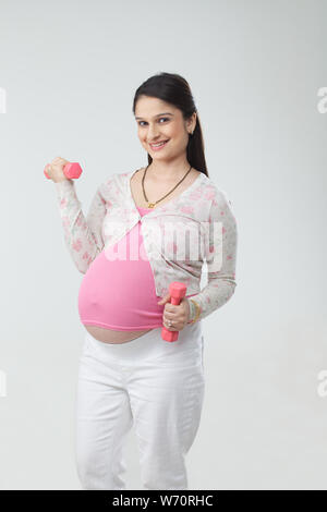 Pregnant woman exercising with dumbbell Stock Photo