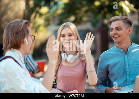 Groupmates giving each other goodbye high-five outside. Stock Photo