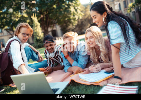 Students watching a movie lying on a blanket together. Stock Photo