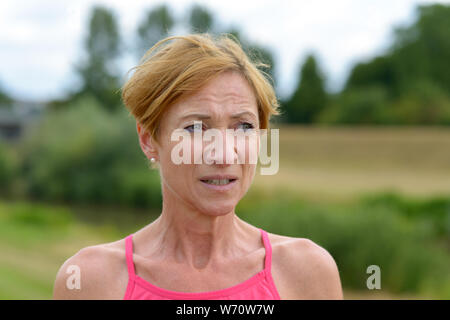 Worried concerned woman frowning as she looks to the side with a thoughtful watchful expression in a close up portrait outdoors Stock Photo