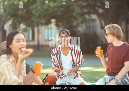 Handsome boy laughing eating with his friends. Stock Photo