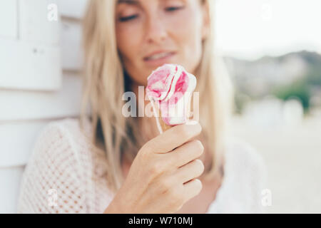 Woman 30 holds in her hands the melting strawberry ice cream in the cone in her hands Stock Photo
