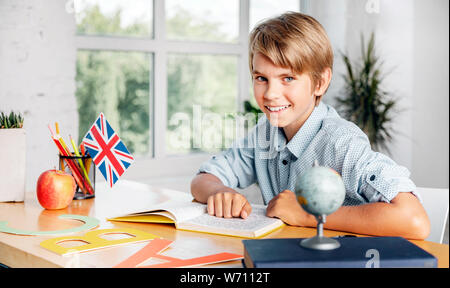 Smart schoolboy reading english textbook, studying languages in early age, modern education Stock Photo