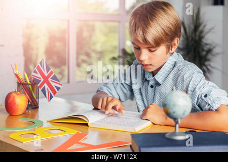 Smart schoolboy reading english textbook, studying languages in early age, modern education Stock Photo