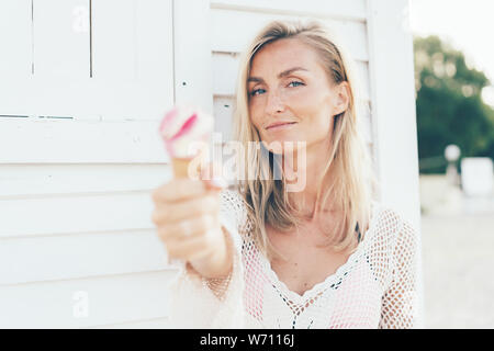 Young European woman holds melted strawberry ice cream in waffle cone Stock Photo