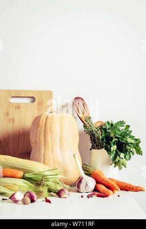 Autumn vegetables and kitchen utensils on table wall background. Seasonal food concept. Stock Photo