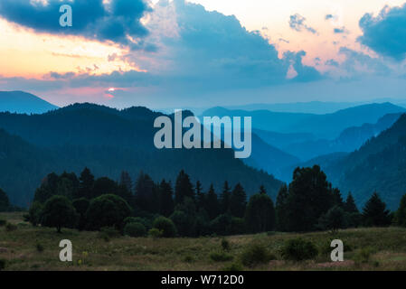 Beautiful dramatic sunset in the mountains. Landscape with sun light shining through orange clouds Stock Photo