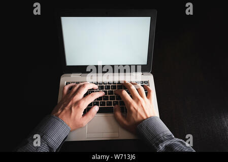 Close up of business man hands working on laptop computer with blank screen in office. Business, digital technology, social network concept Stock Photo