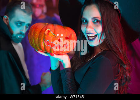Creepy young woman dressed up in a witch costume for halloween. Friends celebrating halloween. Stock Photo