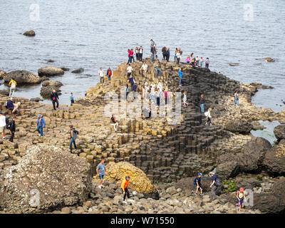County Antrim, Northern Ireland, UK – July 17, 2019: Visitors on Giant’s Causeway, unique hexagonal geological formation of volcanic basalt rocks. Stock Photo