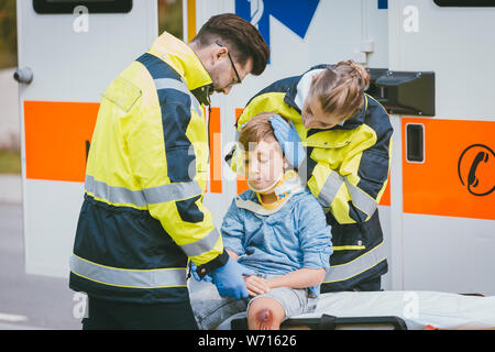 Boy is injured after accident, medics taking care of him Stock Photo