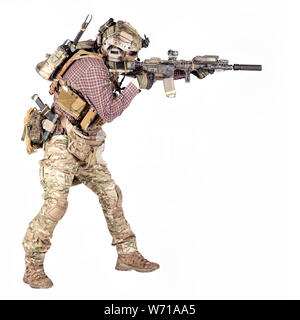 Full length portrait of airsoft player in checkered shirt, wearing camouflage uniform, helmet with tactical radio headset, body armour, aiming with service rifle replica studio shoot isolated on white Stock Photo