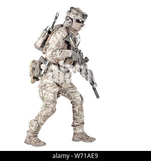 Army soldier, equipped infantryman, airsoft player in camouflage battle uniform, helmet and tactical radio headset jumping, running with assault rifle in hand studio shoot isolated on white background Stock Photo