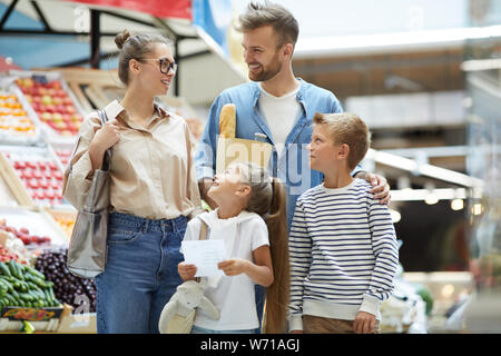 Portrait of contemporary family with two kids shopping at farmers market, copy space Stock Photo