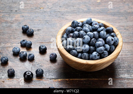 Freshly picked blueberries in wooden bowl on wooden background. Healthy eating and nutrition. Stock Photo