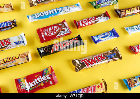 Kiev, Ukraine, March 29, 2018. different chocolate bars of modern companies. Chocolates lie in rows on a yellow background. Skittles - sweets, which a Stock Photo