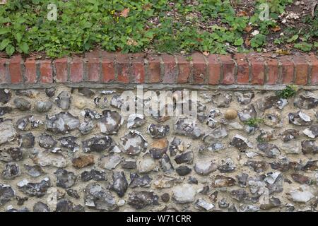 Grey flint stone wall topped with bricks Stock Photo