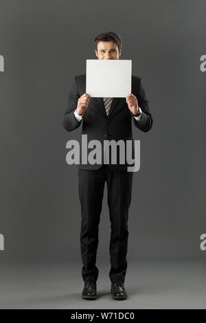 Businessman hiding behind a placard Stock Photo