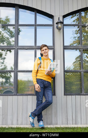 Full length portrait of smiling student posing confidently outdoor in college campus, copy space Stock Photo