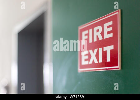 Fire exit sign mounted on the green wall of the corridor. Stock Photo