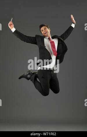 Businessman jumping and holding a credit card Stock Photo