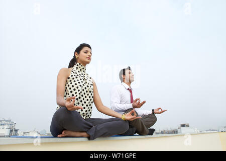 Two business executives sitting in yoga pose Stock Photo