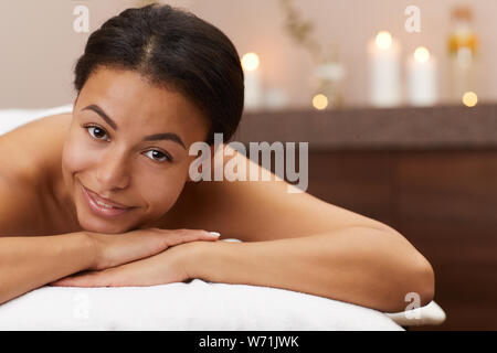 Portrait of beautiful mixed-race woman smiling at camera while relaxing in luxury SPA, copy space Stock Photo