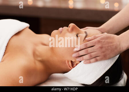 Closeup portrait of beautiful mixed-race woman enjoying face massage in luxury spa, copy space Stock Photo