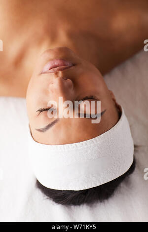 Above view portrait of beautiful mixed-race woman lying on massage table with eyes closed while enjoying SPA, copy space Stock Photo