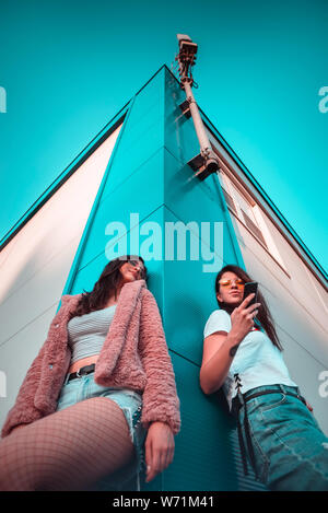 Two young female friends using mobile phone low angle shot Stock Photo