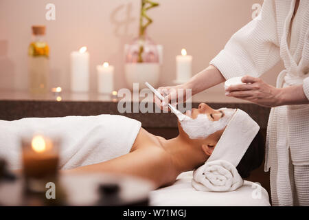 Side view portrait of beautiful mixed race woman enjoying facial therapy in spa, copy space Stock Photo