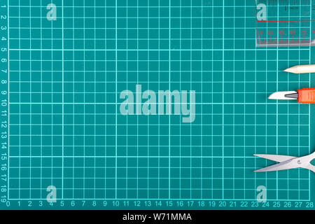 Knives cutter, pencil, scissor and stationary on white green cutting mat background. Selective focus and copy space Stock Photo