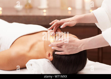 Portrait of beautiful woman enjoying facial therapy while lying on massage table in luxury spa, copy space Stock Photo