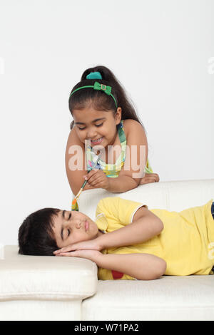 Girl painting her brother face Stock Photo