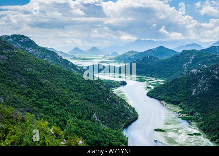 Montenegro, Spectacular green mountains surrounding crnojevica river water with tour boats on it near skadar lake Stock Photo