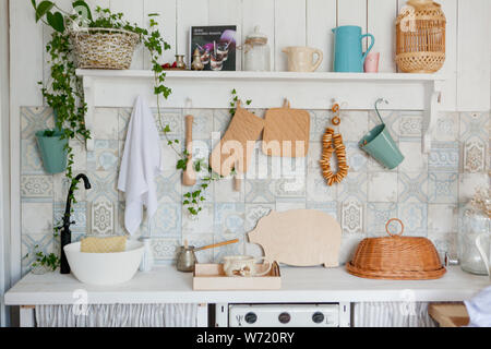 Kitchen towel and glove on work top in modern kitchen, kitchen accessories hanging in the roof rail on the white wall. Stock Photo